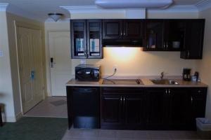 a kitchen with black cabinets and a sink and a microwave at Nova Inn Inuvik in Inuvik