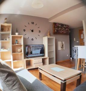 un soggiorno con TV e orologio a muro di Cozy & Quiet Apartment. a Sada