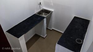 uma casa de banho com um balcão preto e um lavatório em Orange Sky Inn em Canacona