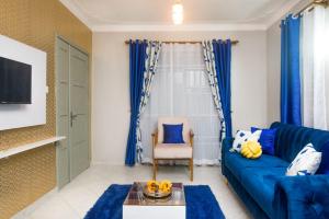 a living room with a blue couch and a chair at Boujee Residence Apartment in Kampala