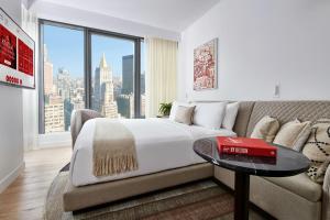 ニューヨークにあるVirgin Hotels New York Cityのベッドルーム(ベッド1台、ソファ、大きな窓付)