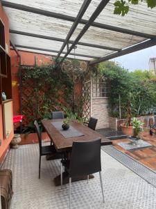 un patio con una mesa de madera y sillas bajo una pérgola en Al 20 Guest House Fiera Milano - Certosa - San Siro, en Milán