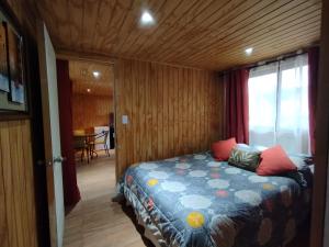 um quarto com uma cama num quarto de madeira em El Fogon de Rio Claro em Rio Claro