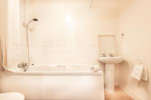 een witte badkamer met een bad en een wastafel bij BEST PRICE! STUNNING 2 Bed City Centre - 4 single beds or 2 Super king, Smart TVs, Sofa Bed & FREE SECURE PARKING in Southampton