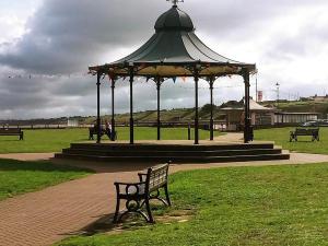 a bench in a park with a gazebo at Seashells Cottage in Gorleston-on-Sea