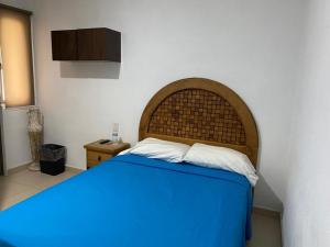 um quarto com uma cama azul e uma cabeceira em madeira em Estancia Santa Fe em Celaya