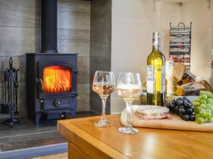 a table with two glasses of wine and a stove at Liftingstane Dairy Cottage in Closeburn