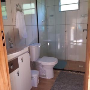 a bathroom with a toilet and a shower and a sink at Portal da alvorada in Praia Grande