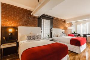 two beds in a room with a brick wall at Hôtel des Coutellier in Quebec City