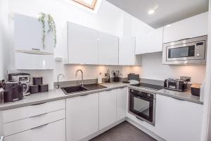 eine weiße Küche mit weißen Schränken und Geräten in der Unterkunft Coasters in Aldeburgh