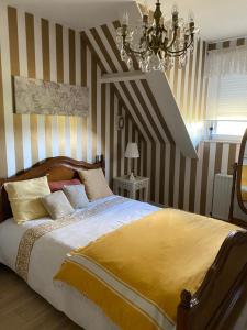 ein Schlafzimmer mit einem Bett mit gestreiften Wänden und einem Kronleuchter in der Unterkunft L’hirondelle du Faubourg 