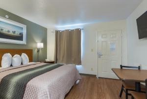 a hotel room with a bed and a table and a door at HomeTowne Studios by Red Roof Dallas - Irving in Irving