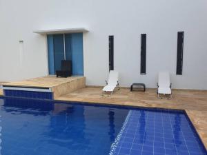 a swimming pool with two chairs next to a building at Girardot Casa estilo mediterraneo con piscina privada in Girardot