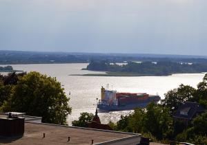 a large container ship traveling down a river at Das Elbcottage - Remise am Süllberg - Boarding House in Hamburg