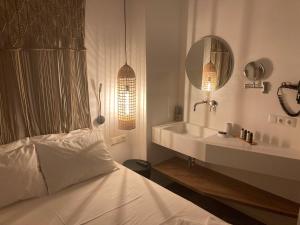 a bedroom with a bed and a sink and a mirror at Ninemia Naxos Suites in Naxos Chora