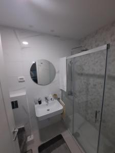 ein Bad mit einer Dusche, einem Waschbecken und einem Spiegel in der Unterkunft Mia Apartments in Podgorica