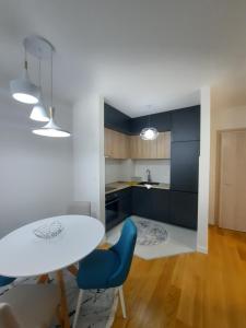 eine Küche mit einem weißen Tisch und blauen Stühlen in der Unterkunft Mia Apartments in Podgorica