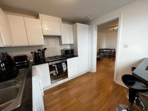 a kitchen and living room with white cabinets and wooden floors at River View Apartment - Central Dundee - Free Private Parking - Sky & TNT Sports - Lift Access - Superfast WIFI - Quiet Neighbourhood - 2 Bathrooms - Amazing Views - Balcony & Courtyard - Long Stays Welcome in Dundee