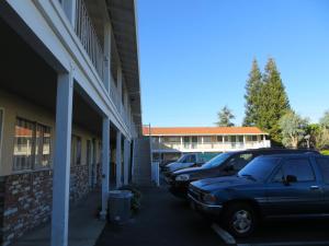 een paar auto's geparkeerd naast een gebouw bij Capri Motel in Santa Clara