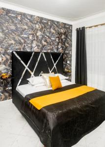 a bedroom with a large black bed with yellow pillows at Boujee Residence Apartment in Kampala
