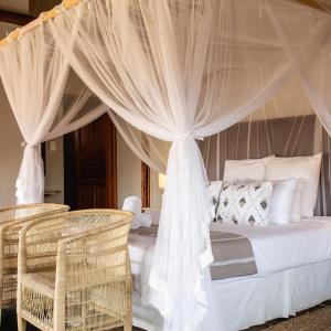 una camera da letto con letto, tende e sedie in vimini di Rain Farm Game Lodge a uMhlali