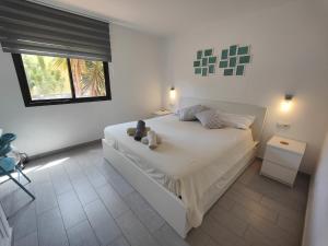 sypialnia z dużym białym łóżkiem i oknem w obiekcie Corralejo Happy Place, precioso apartamento con piscina w Corralejo +37 zdjęć