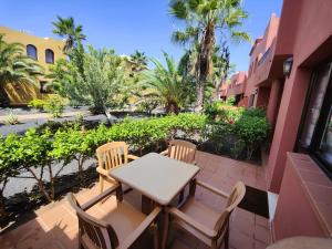 stół i krzesła na patio z palmami w obiekcie Corralejo Happy Place, precioso apartamento con piscina w Corralejo