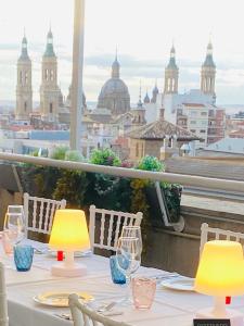 a table with wine glasses and a view of a city at Aparthotel Los Girasoles in Zaragoza