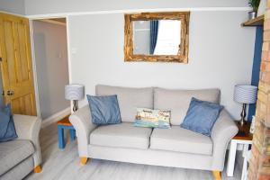 sala de estar con sofá y espejo en Seagull Cottage - Suffolk Coastal Escapes, en Pakefield