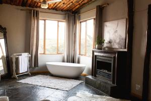 a bathroom with a large tub in front of a fireplace at Rain Farm Game Lodge in uMhlali