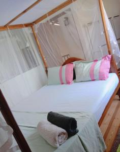 1 cama en una tienda de campaña con almohadas rosas y blancas en Romaclan Villa, en Midigama East