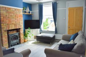 a living room with a couch and a fireplace at Seagull Cottage - Suffolk Coastal Escapes in Pakefield