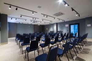 a conference room with blue chairs and a podium at Hotel Darolt Criciúma in Criciúma