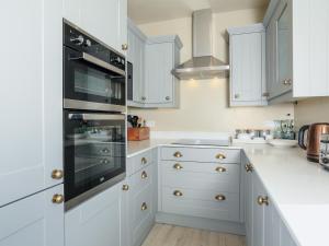 a kitchen with white cabinets and black appliances at Ferrystone in Dartmouth