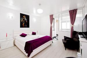 a white bedroom with a large bed and a chair at SUNSET RIVER STUDIO in Galaţi