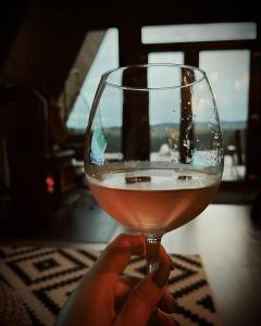 a person is holding a glass of wine at Nordik Cabin - Aframe with 2 bedrooms in Mărişel