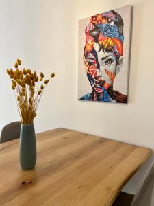 a vase on a table with a painting on the wall at Amplio y luminoso apartamento en el centro in Don Benito
