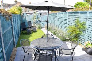 a table and chairs with an umbrella on a patio at Seagull Cottage - Suffolk Coastal Escapes in Pakefield