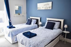 two beds in a bedroom with blue walls at Seagull Cottage - Suffolk Coastal Escapes in Pakefield