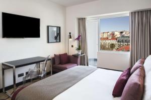 a hotel room with a bed and a desk and a window at Avani Avenida Liberdade Lisbon Hotel in Lisbon