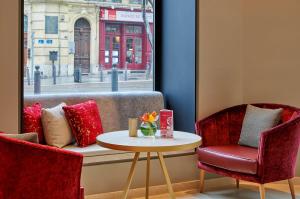 een tafel en 2 stoelen in een kamer met een raam bij NH Collection Marseille in Marseille