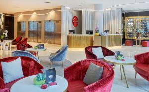 a lobby with red chairs and tables and a counter at NH Collection Marseille in Marseille