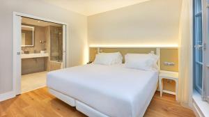 a bedroom with a large white bed and a bathroom at NH Collection Marseille in Marseille