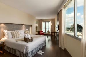 a hotel room with a bed and a large window at NH Lyon Airport in Saint-Exupéry