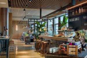 un restaurante con barra y taburetes en una habitación en NH Lyon Airport, en Saint-Exupéry