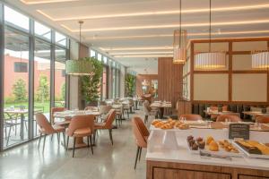 a dining room with tables and chairs and windows at NH Porto Jardim in Porto