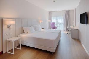 a white bedroom with a large bed and a tv at NH Lecco Pontevecchio in Lecco