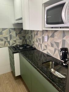 uma cozinha com um lavatório e um micro-ondas em Aruanã Suite Green em Vila Velha