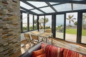 a conservatory with a table and chairs and a view of the ocean at Finca Marina BuenVivir in Tazacorte