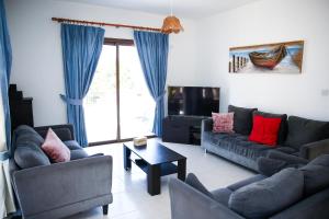 a living room with two couches and a tv at VILLA LAMBRIANA in Peyia